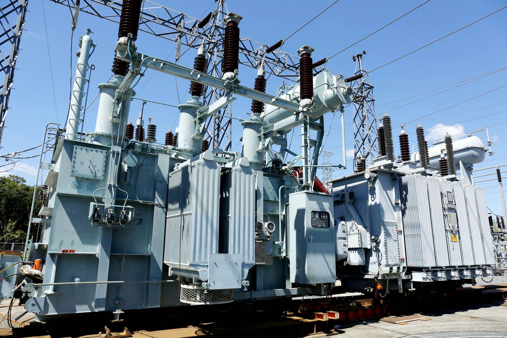 Große elektrische Transformatoren in einem Umspannwerk mit Kabeln und Ausrüstung